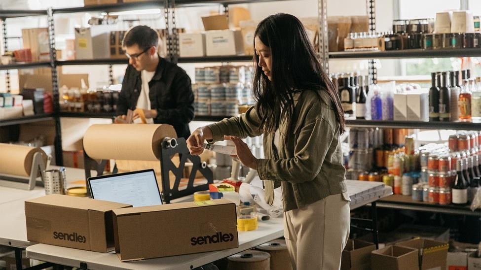 Small business team packing online orders at a worktable in a stockroom